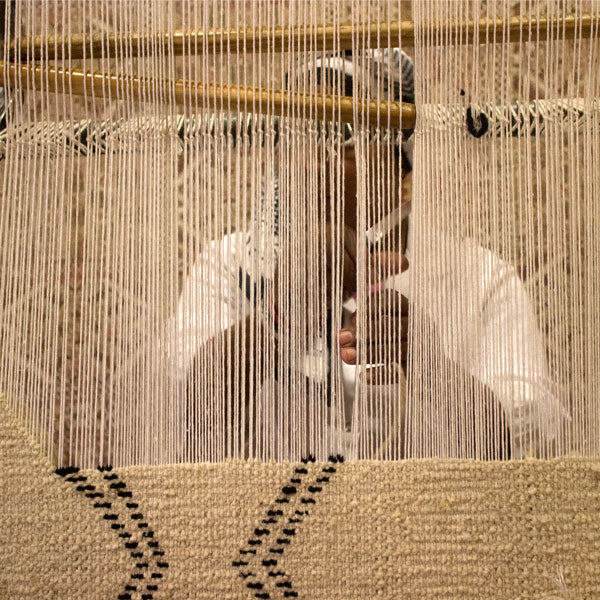 Artisan hand weaving a moroccan rug