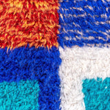 Jovial Moroccan Rug, a blue, red, and tangerine on natural white wool, showcasing the eclectic style of Berber women