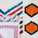 Prosperity Runner Moroccan Rug: featuring white, blue, tangerine, red, and black colors. Handcrafted with tribal symbols